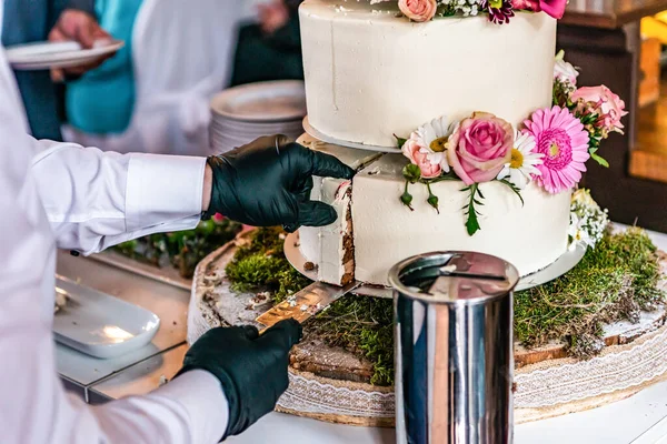 Cortar um belo bolo de casamento delicioso em muitos níveis com flores silvestres frescas e rosas — Fotografia de Stock