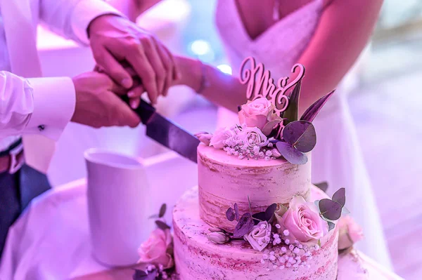 Vágás egy gyönyörű finom esküvői torta sok szinten friss vad virágok és rózsák — Stock Fotó