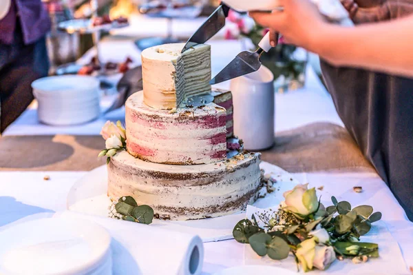 Cortar um belo bolo de casamento delicioso em muitos níveis com flores silvestres frescas e rosas — Fotografia de Stock
