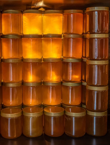 Torre y filas de miel amarilla dorada en tarro de vidrio sobre tabla de madera Primer plano Copiar espacio — Foto de Stock