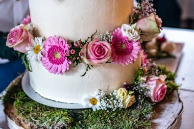 Güzel, lezzetli düğün pastası taze çiçekler ve güllerle dolu katlarda.