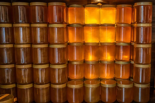 Torre e fileiras de mel amarelo dourado em frasco de vidro na placa de madeira Fechar Copiar espaço — Fotografia de Stock