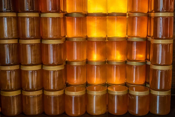 Torre e fileiras de mel amarelo dourado em frasco de vidro na placa de madeira Fechar Copiar espaço — Fotografia de Stock