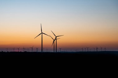 Rüzgâr türbinlerinin siyah silueti enerji jeneratörü Almanya 'da bir rüzgar çiftliğinde gün batımında