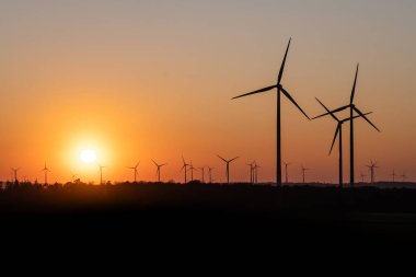 Rüzgâr türbinlerinin siyah silueti enerji jeneratörü Almanya 'da bir rüzgar çiftliğinde gün batımında