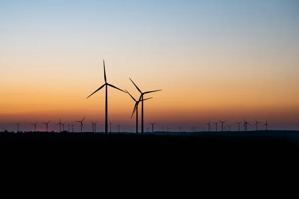 Zwart silhouet van windturbines energiegenerator op verbazingwekkende zonsondergang op een windpark in Duitsland — Stockfoto