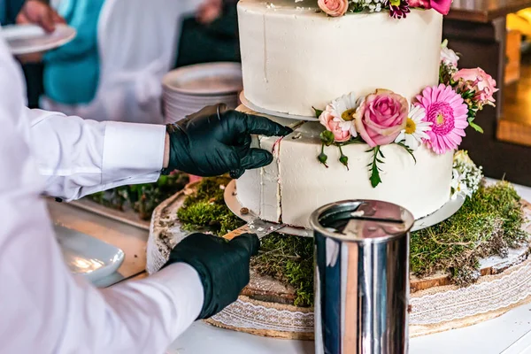 Cortar um belo bolo de casamento delicioso em muitos níveis com flores silvestres frescas e rosas — Fotografia de Stock