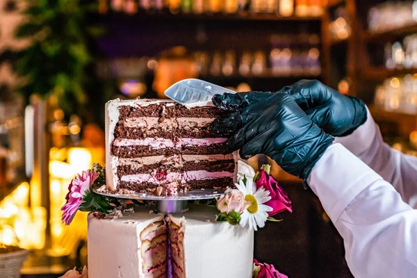 Cortar un delicioso hermoso pastel de boda en muchos niveles con flores silvestres frescas y rosas — Foto de Stock