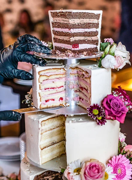 Cortar un delicioso hermoso pastel de boda en muchos niveles con flores silvestres frescas y rosas — Foto de Stock