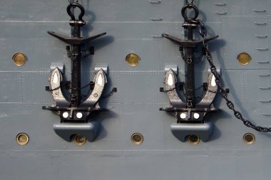 Gemilerin gövdesine zincirlenmiş iki büyük gemi çapası. Metal yapı deniz gücünü, güvenilirliği ve deniz geleneklerini sembolize eder..