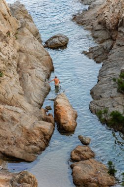 Kıdemli adam Fenals Sahili, Iloret de mar, İspanya 'da Akdeniz' in sığ sularında yürüyüş yapıyor.