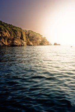 Costa Brava kıyılarının manzarası kayalık uçurumlar, yemyeşil yemyeşil ve ılık gün batımında parlayan sakin deniz suları..