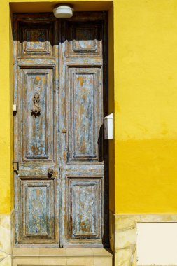 Sarı boyalı ahşap kapısı ve duvarıyla bir yerleşim bölgesinde, güneşten korunan güzel bir Akdeniz evi..