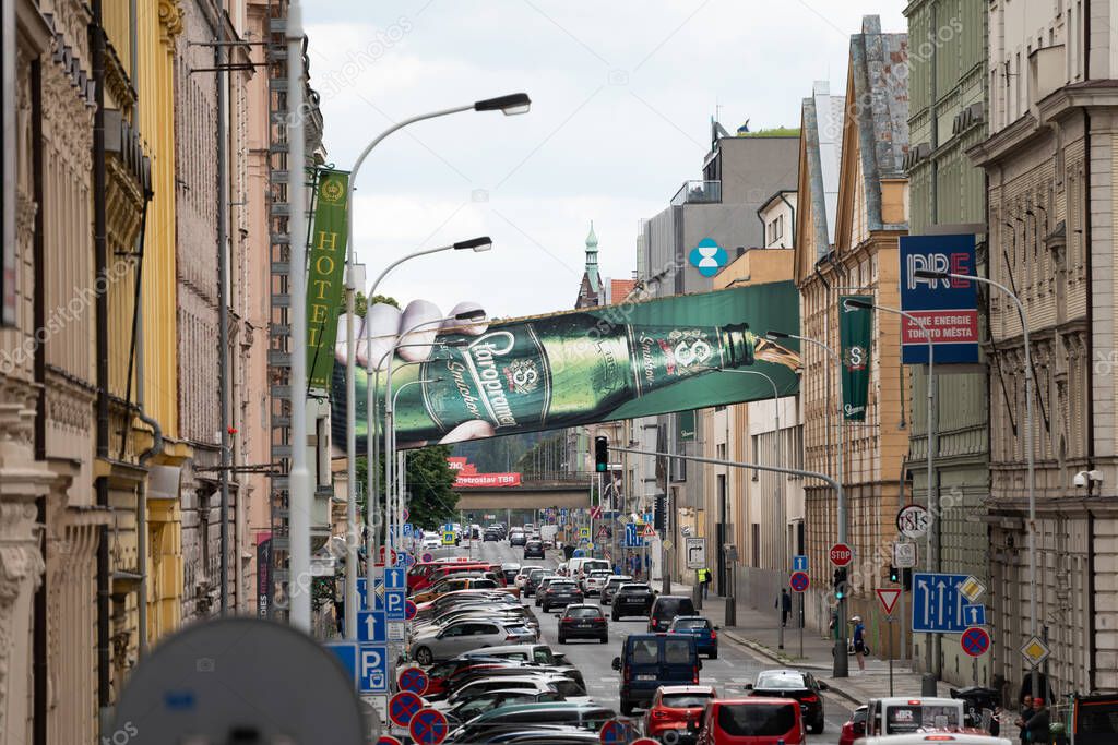 PRAGUE, CZECHIA - 30. May 2025: Staropramen beer bottle advertisement at the building exterior of the brewery in Smichov. Bridge above a busy street in the city.