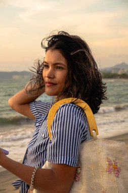 Günbatımında plajda meditasyon yapan ve özgürlüğünün tadını çıkaran Latin bir kadın. Deniz, sükunet, tatil, doğa ve Latin Amerika kavramları. Yüksek kalite fotoğraf