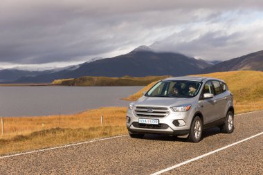 Genç bir çift bir araba kullanıyor, İzlanda dağ manzarası