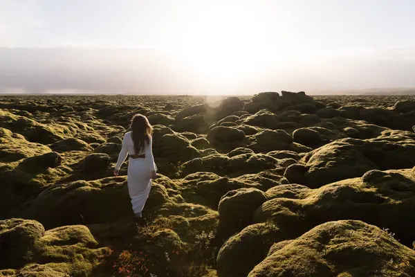Young white woman in white warm clothes is enjoying sunset in the middle of eldhraun lava field