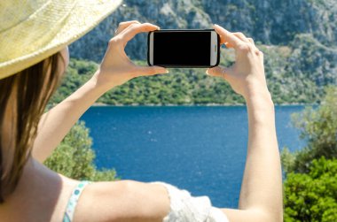 Geri kalan beyaz smartphone yat güneşli gün arka plan kopya alanı üstten görünüm hafta sonları deniz suyu üzerinde tutarak yaz şapkalı kadın tatil