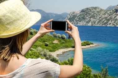 Geri kalan beyaz smartphone yat güneşli gün arka plan kopya alanı üstten görünüm hafta sonları deniz suyu üzerinde tutarak yaz şapkalı kadın tatil