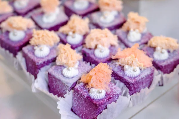 Delicious wedding reception sweets luxury purple color desserts with edible pearl and edible crystal stones on top on glass plate. Candy bar desser.