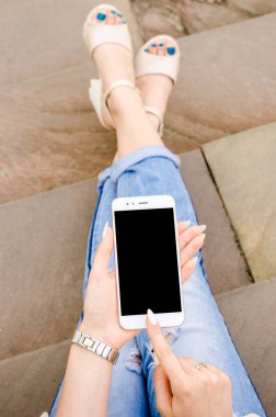 Yakın kadar beyaz Smartphone cep cep kadın şık yırtık kot uzun çivi Denim siyah Oled ekran taş arka plan ellerimi