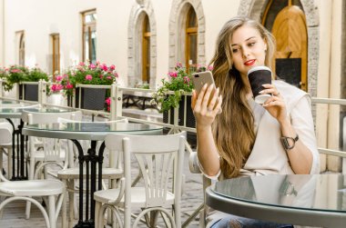 Çağrı smartphone telefon hücre içinde café şehir sokak güneşli gün geçmiş uzun saçlı tutan bussines casual kadın gülümseyerek