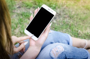 Yakın kadar beyaz Smartphone cep cep kadın şık yırtık kot uzun çivi Denim siyah Oled ekran doğa arka plan ellerimi