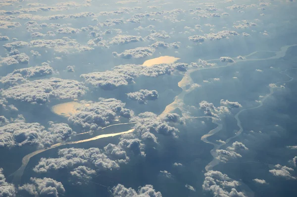 Uçak pencere Dünya'dan görünüm nehir ve bulutlar seyahat turizm İstanbul Türkiye zemin. Bulutların üzerinde zemin üzerinde bulutlu fırtınalı gökyüzü uçan bir uçağın kanat.