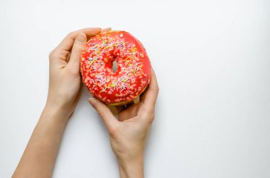 Kadın el ile pembe çörek tutarak ekstra kalori yağ lokanta aşırı kilo sağlıksız sarı zemin üzerine sprinkles.