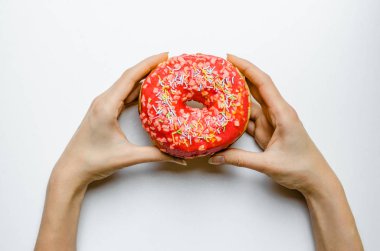 Kadın el ile pembe çörek tutarak ekstra kalori yağ lokanta aşırı kilo sağlıksız sarı zemin üzerine sprinkles.