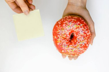 Pembe çörek sprinkles ile ekstra kalori tutan kadın el lokanta aşırı kilo sarı arka plan üzerinde sağlıksız şişko