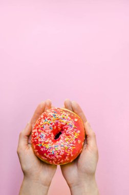 Pembe çörek sprinkles ile ekstra kalori tutan kadın el lokanta aşırı kilo sarı arka plan üzerinde sağlıksız şişko