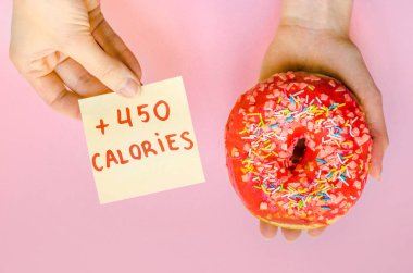 Pembe çörek sprinkles ile ekstra kalori tutan kadın el lokanta aşırı kilo sarı arka plan üzerinde sağlıksız şişko