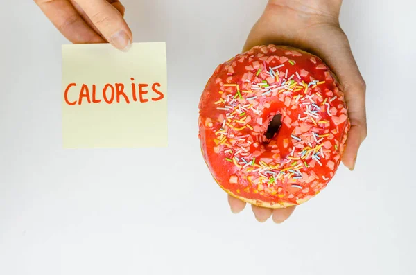 妇女手拿着粉红色的甜甜圈与洒额外的卡路里脂肪快餐过量体重不健康的黄色背景 — 图库照片