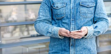 Yakın kadar Hipster iş adamı kullanarak akıllı cep telefonu App açık siyah Oled ekran arka plan Denim Jeans Gömlek şık giyinmiş