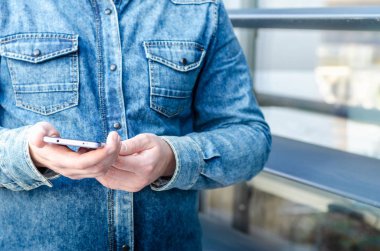 Yakın kadar Hipster iş adamı kullanarak akıllı cep telefonu App açık siyah Oled ekran arka plan Denim Jeans Gömlek şık giyinmiş