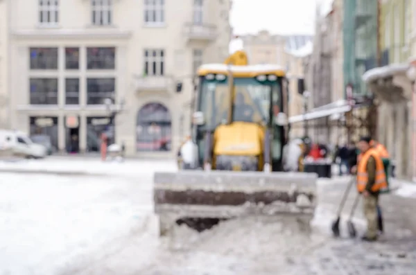 Blurred winter background city snow cleaner technician tractor removes snow communal services life bad weather lifestyle blizzard christmas cold falls snow tourists panorama old city