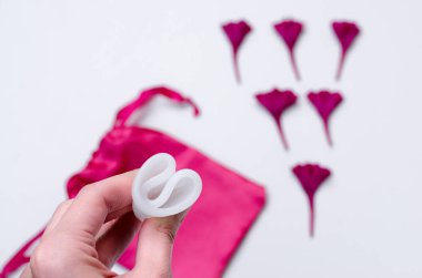 Pembe arka plan sağlık qynecology kavramı beyaz adet fincan sıhhi peçete tampon tutan kadın el yakın 