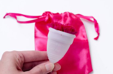 Pembe arka plan sağlık qynecology kavramı beyaz adet fincan sıhhi peçete tampon tutan kadın el yakın 
