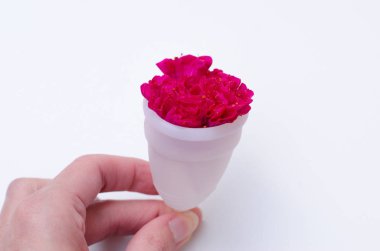 Pembe arka plan sağlık qynecology kavramı beyaz adet fincan sıhhi peçete tampon tutan kadın el yakın 