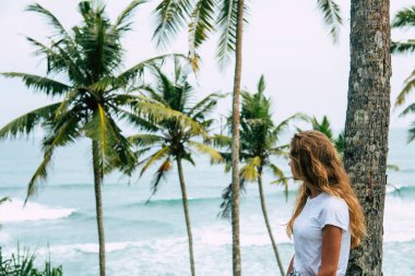 Tropikal bir plajda palmiye ağacı üzerinde genç güzel gelin. Tropikal gökyüzü içinde belgili tanımlık geçmiş. Yaz tatil kavramı. Broidered Sri Lanka