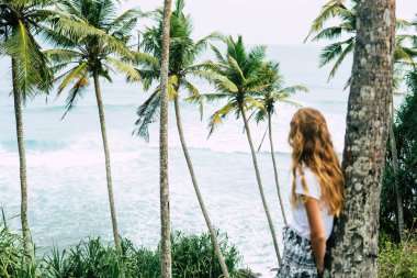 Kadın broidered Sri Lanka plajda palmiye ağacı altında