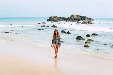 Mutlu bikinili kadın okyanusta yüzerken eğleniyor. Özgürlük bikinili kadın kollarını kaldırmış tropik sahilde neşe içinde su sıçratıyor. Karayipler 'de yaz tatilinde başarılı Asyalı kız.