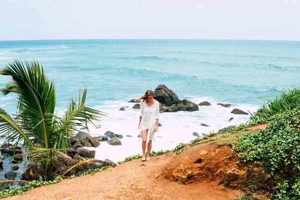 Uzun elbiseli güzel bir kız sahilde broidered Sri Lanka kayalarda duruyor