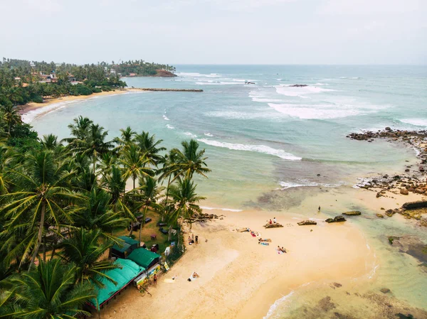 Antenowe, widok z góry z pięknej piaszczystej plaży aerial strzał z błękitne fale toczenia do brzegu plaży, niektóre skały przedstawić Mirisa Sri Lanka — Zdjęcie stockowe