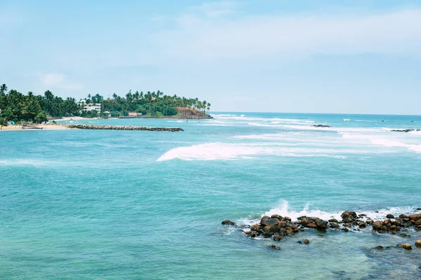 Αμμουδιά με γαλαζοπράσινα καθαρά νερά της θάλασσας, και μερικοί άνθρωποι στην παραλία. Mirisa Σρι Λάνκα — Φωτογραφία Αρχείου