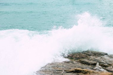 Tehlike dalgası fırtınadan önce kaya kıyısına sprey ve köpükle vuruyor.