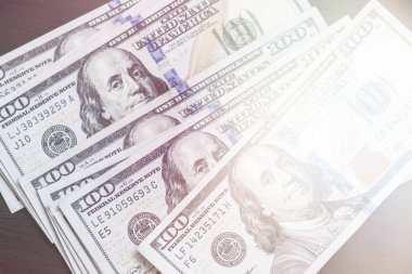 Bize yeni bir siyah Ahşap dokulu masaya yüz dolarlık banknotlar. Işık tonlama