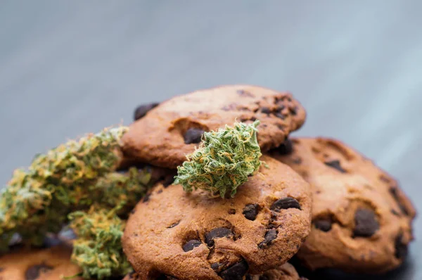 Behandeling van medische marihuana voor gebruik in levensmiddelen Cookies met cannabis en toppen van marihuana op tafel. — Stockfoto