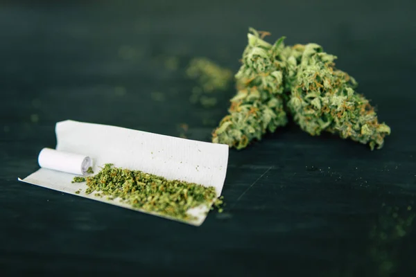 Makro von Cannabisknospen Marihuana mit Trichomen Cannabis zerkleinert Unkraut Joint Weed und zerkleinert Unkraut auf einem schwarzen Tisch — Stockfoto